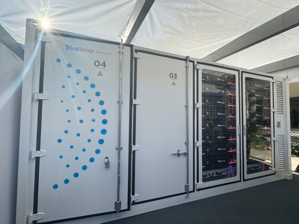 Trina Storage Elementa 2 battery storage enclosure in white with blue detailing, catching the sunlight in an outdoor display setting.